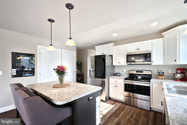 kitchen with white cabinetry, decorative light fixtures, a breakfast bar area, and appliances with stainless steel finishes