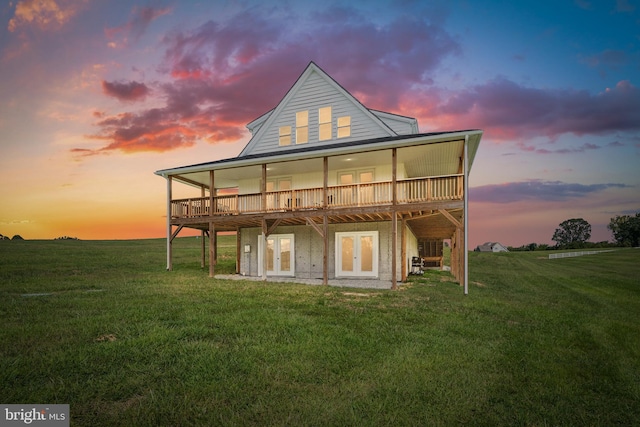 back house at dusk with a deck and a lawn