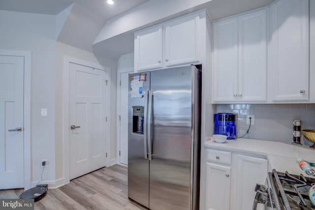 kitchen with light hardwood / wood-style flooring, range, white cabinetry, stainless steel refrigerator with ice dispenser, and decorative backsplash