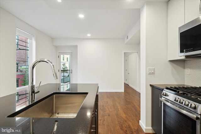 1501 N 31st St Unit 205, Philadelphia, PA 19121 - kitchen featuring dark countertops, a sink, stainless steel appliances, white cabinetry, and backsplash