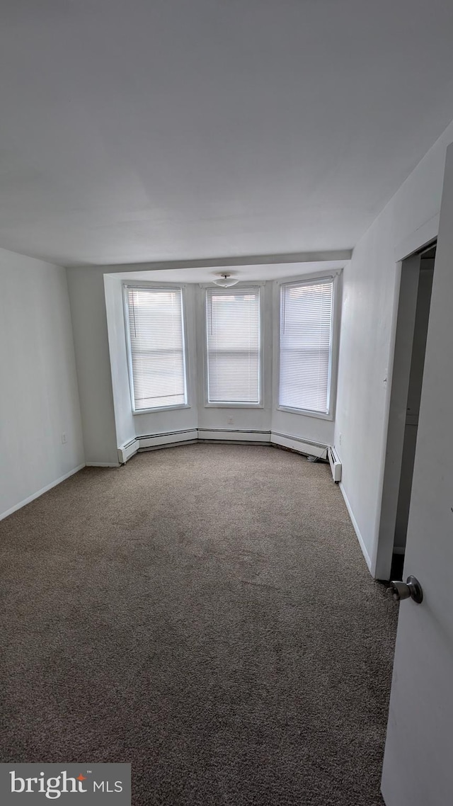 carpeted empty room with baseboard heating and plenty of natural light