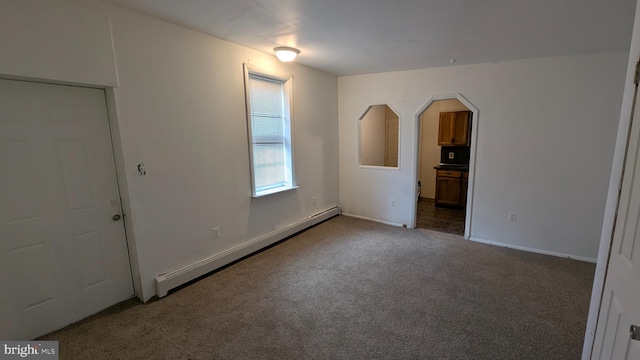 carpeted empty room with a baseboard heating unit