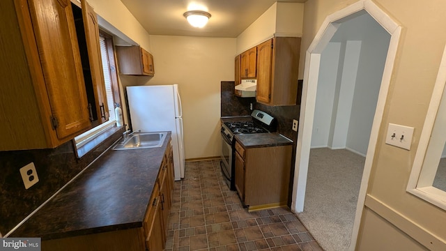 kitchen with gas range, white refrigerator, sink, and backsplash