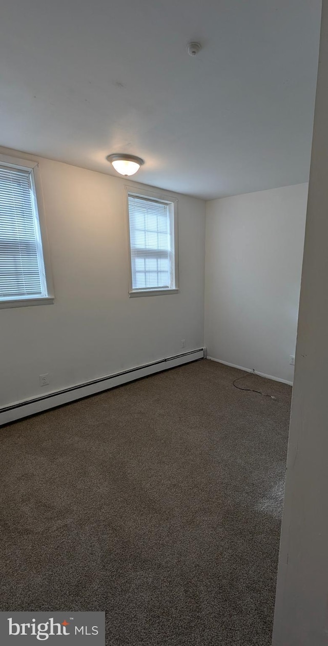 carpeted spare room featuring a baseboard radiator