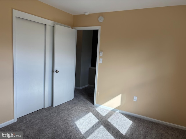 unfurnished bedroom featuring dark carpet and a closet