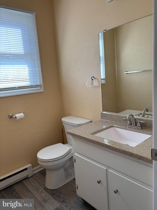 bathroom with a baseboard radiator, wood-type flooring, toilet, and vanity