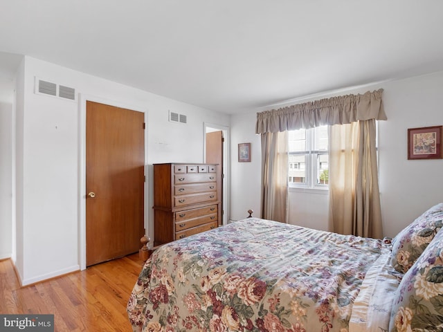 bedroom featuring visible vents, light wood finished floors, and baseboards
