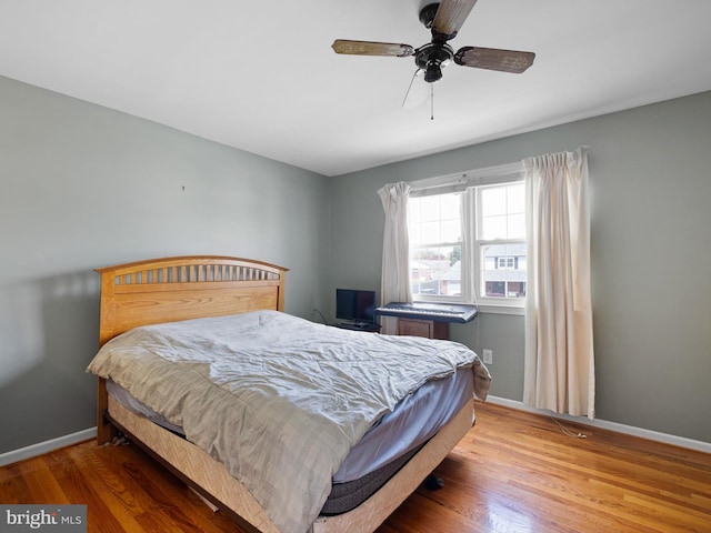 bedroom featuring baseboards, wood finished floors, and a ceiling fan