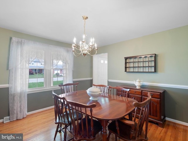 dining area with baseboards, a chandelier, and light wood-type flooring