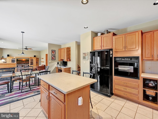 kitchen featuring a breakfast bar area, light tile patterned floors, a kitchen island, pendant lighting, and black appliances