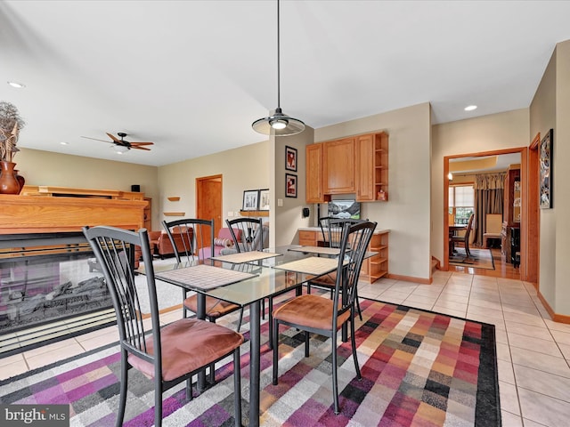 tiled dining room featuring ceiling fan and a multi sided fireplace