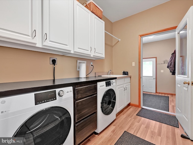 laundry area with sink, light hardwood / wood-style floors, cabinets, and washing machine and clothes dryer