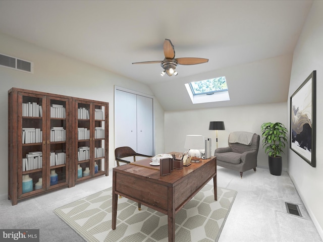 carpeted office space featuring vaulted ceiling with skylight and ceiling fan