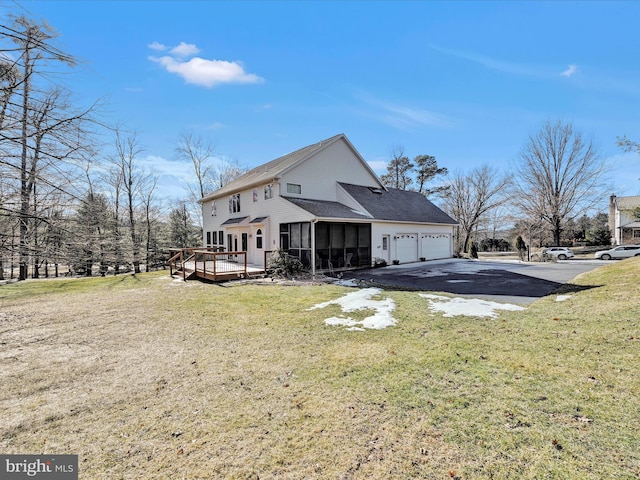 back of house with a garage, a wooden deck, a sunroom, and a yard