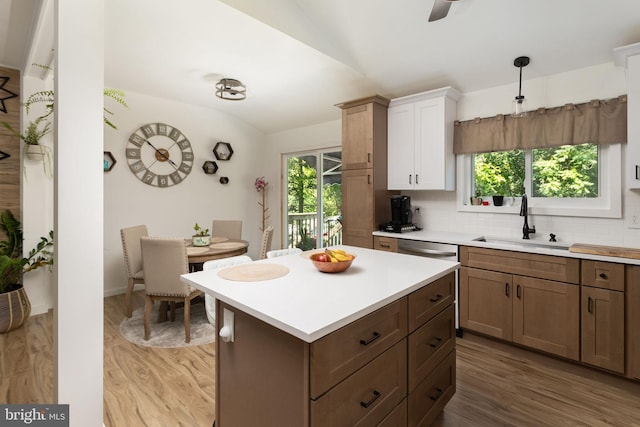 kitchen with sink, light hardwood / wood-style flooring, decorative backsplash, and decorative light fixtures