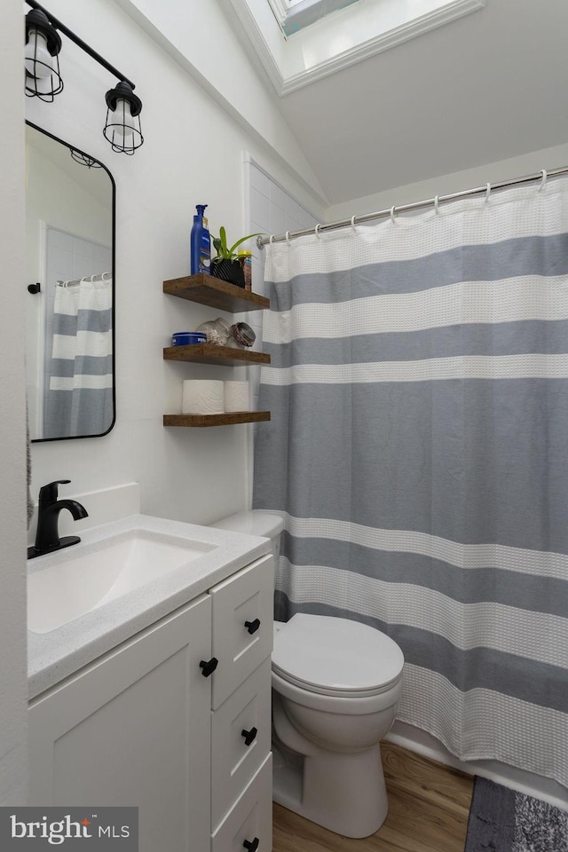 bathroom with hardwood / wood-style flooring, vanity, toilet, and vaulted ceiling