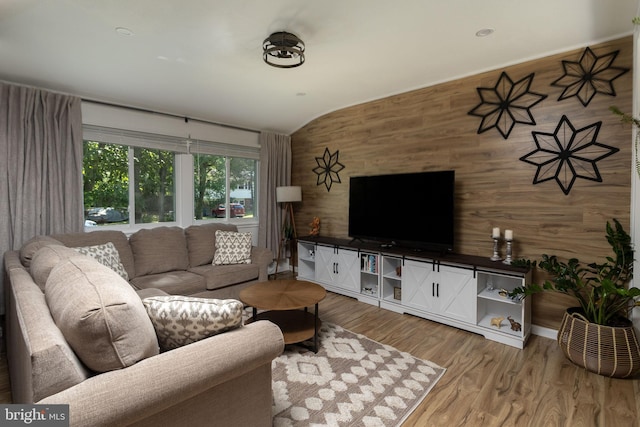 living room with lofted ceiling, hardwood / wood-style floors, and wood walls