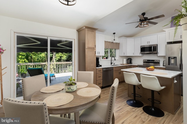 kitchen featuring pendant lighting, sink, appliances with stainless steel finishes, a center island, and light hardwood / wood-style floors