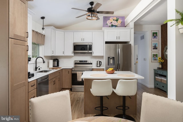 kitchen featuring tasteful backsplash, white cabinetry, sink, a center island, and stainless steel appliances