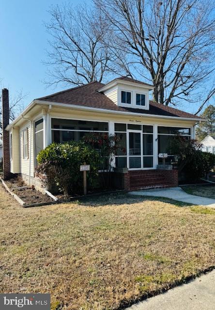 view of front of property featuring a sunroom and a front lawn