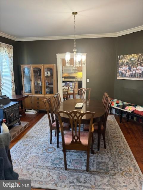 dining area featuring an inviting chandelier, hardwood / wood-style flooring, and ornamental molding