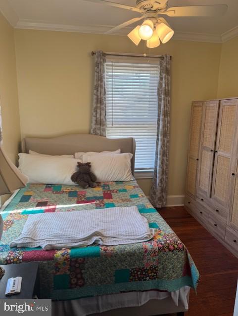 bedroom with crown molding, ceiling fan, and dark hardwood / wood-style flooring