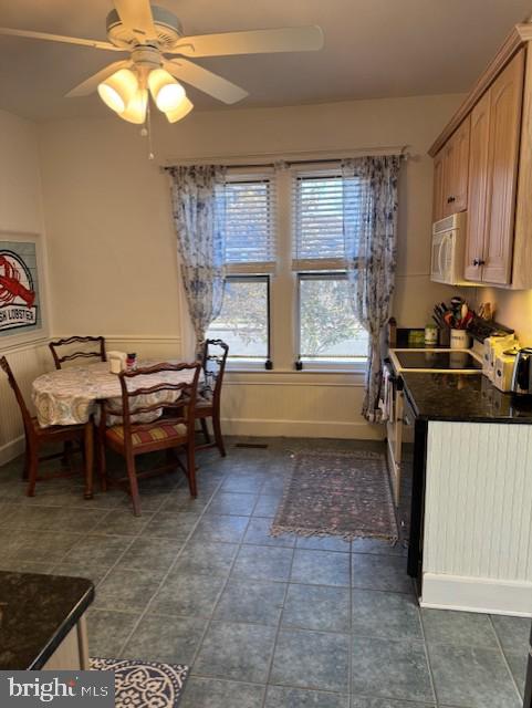 dining area featuring ceiling fan and dark tile patterned floors