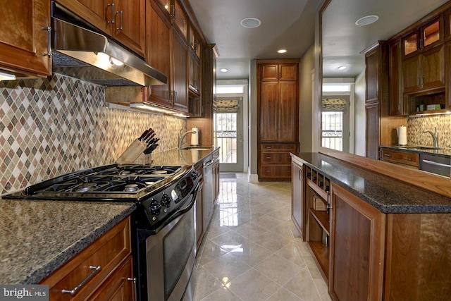 kitchen featuring dark stone countertops, appliances with stainless steel finishes, sink, and light tile patterned floors