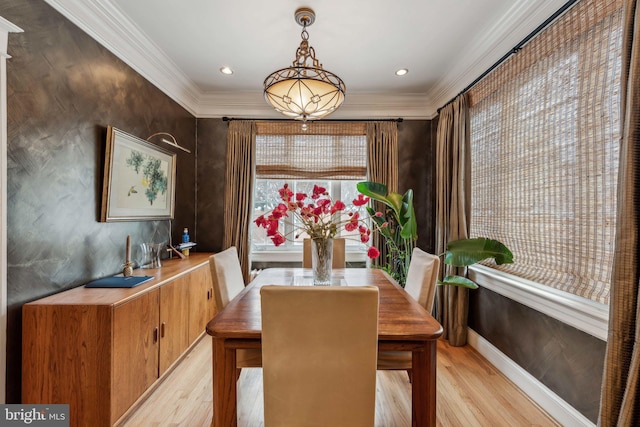 dining area with ornamental molding and light hardwood / wood-style floors