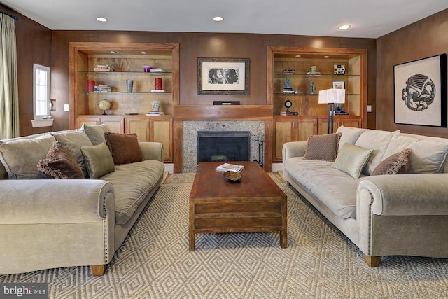 living room featuring built in shelves, a premium fireplace, and wood walls