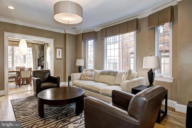 living room with crown molding, a healthy amount of sunlight, and light wood-type flooring