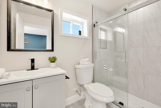 bathroom with a stall shower, baseboards, vanity, and toilet