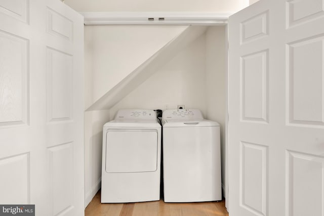 laundry area with laundry area, washer and clothes dryer, and light wood-type flooring