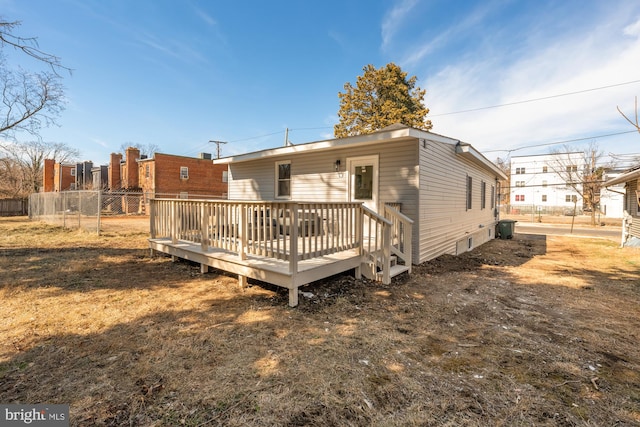 back of property featuring a yard, a wooden deck, and fence