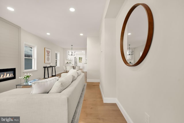 living area featuring a healthy amount of sunlight, light wood finished floors, a fireplace, and recessed lighting