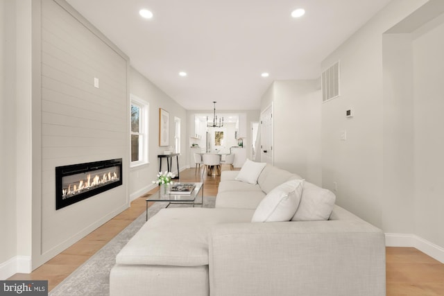 living area featuring light wood-style flooring, visible vents, a chandelier, and recessed lighting