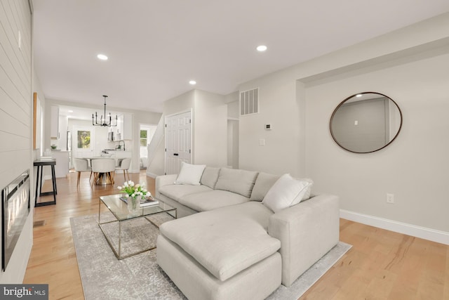 living area with baseboards, visible vents, an inviting chandelier, light wood-style floors, and recessed lighting