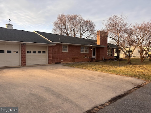 ranch-style home with a garage and a front lawn