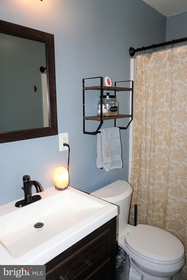 bathroom featuring walk in shower, vanity, and toilet