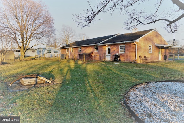 back of property with a yard and an outdoor fire pit