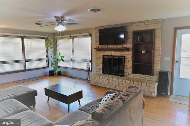 living room with ceiling fan, a fireplace, and light hardwood / wood-style floors