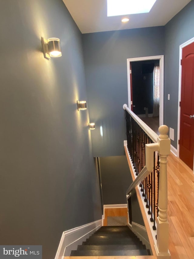 stairway with hardwood / wood-style flooring and a skylight