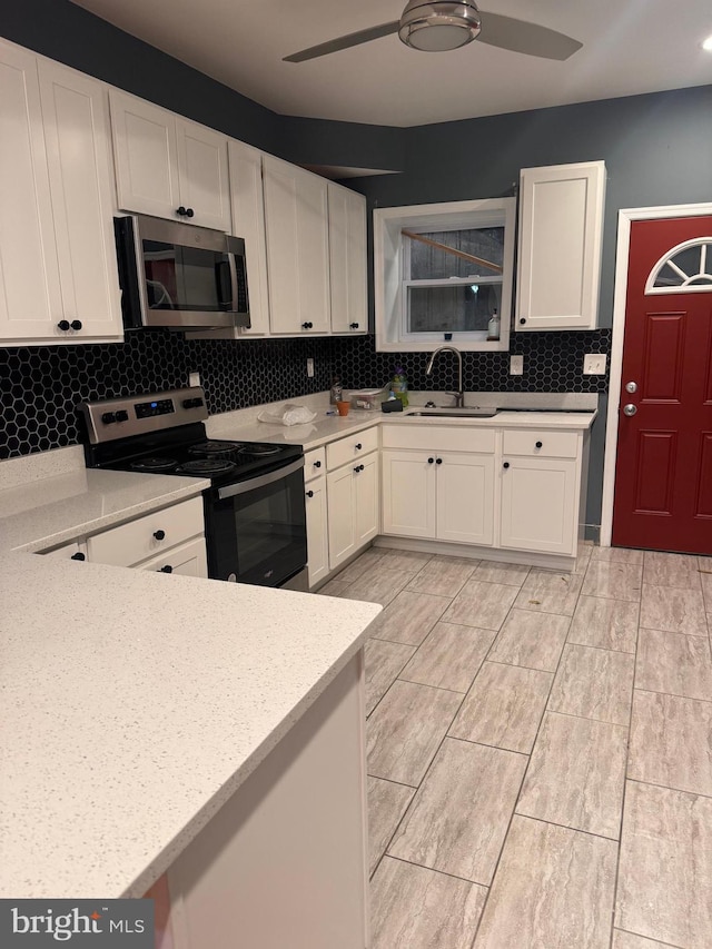 kitchen featuring sink, tasteful backsplash, ceiling fan, stainless steel appliances, and white cabinets