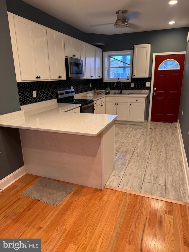 kitchen with white cabinetry, appliances with stainless steel finishes, sink, and kitchen peninsula