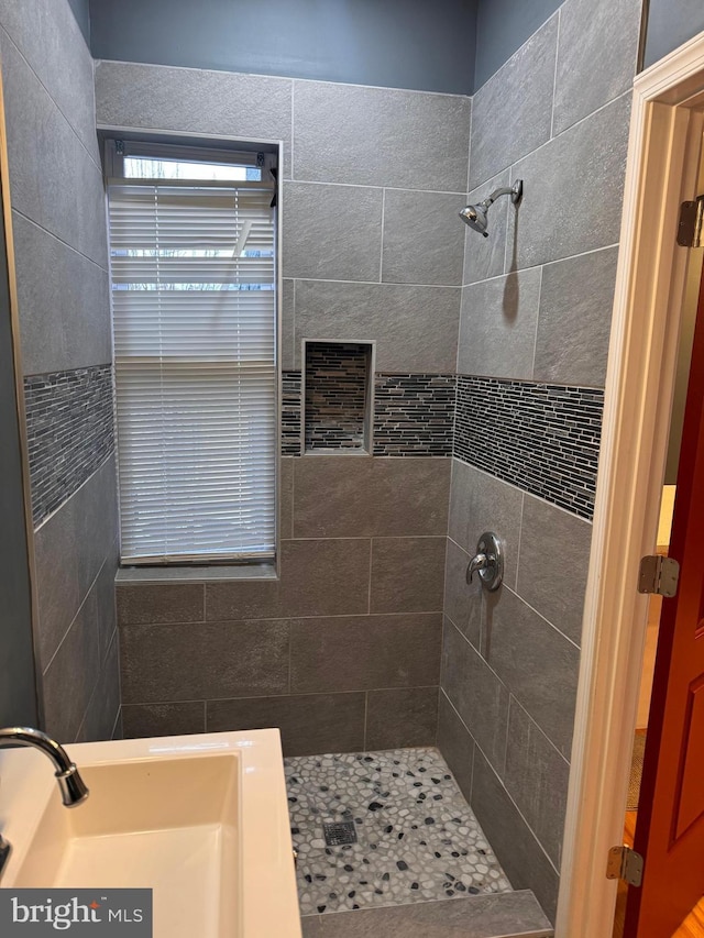 bathroom with tiled shower and sink