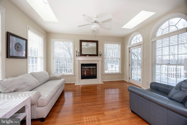 living room featuring a skylight, ceiling fan, and wood-type flooring