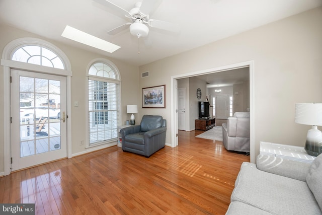 living room with a skylight, hardwood / wood-style floors, and ceiling fan