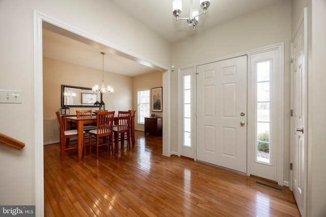 foyer with wood-type flooring and a notable chandelier