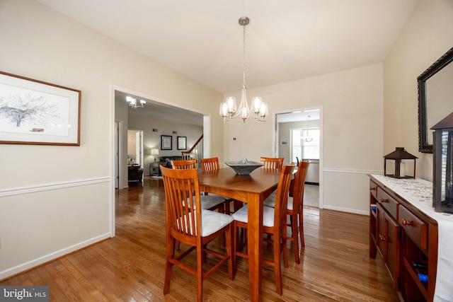 dining space with dark wood-type flooring and a notable chandelier