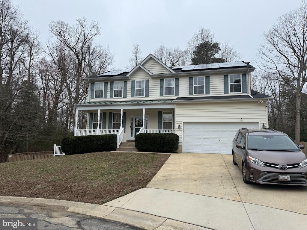 view of front of home with driveway, solar panels, a standing seam roof, covered porch, and a garage